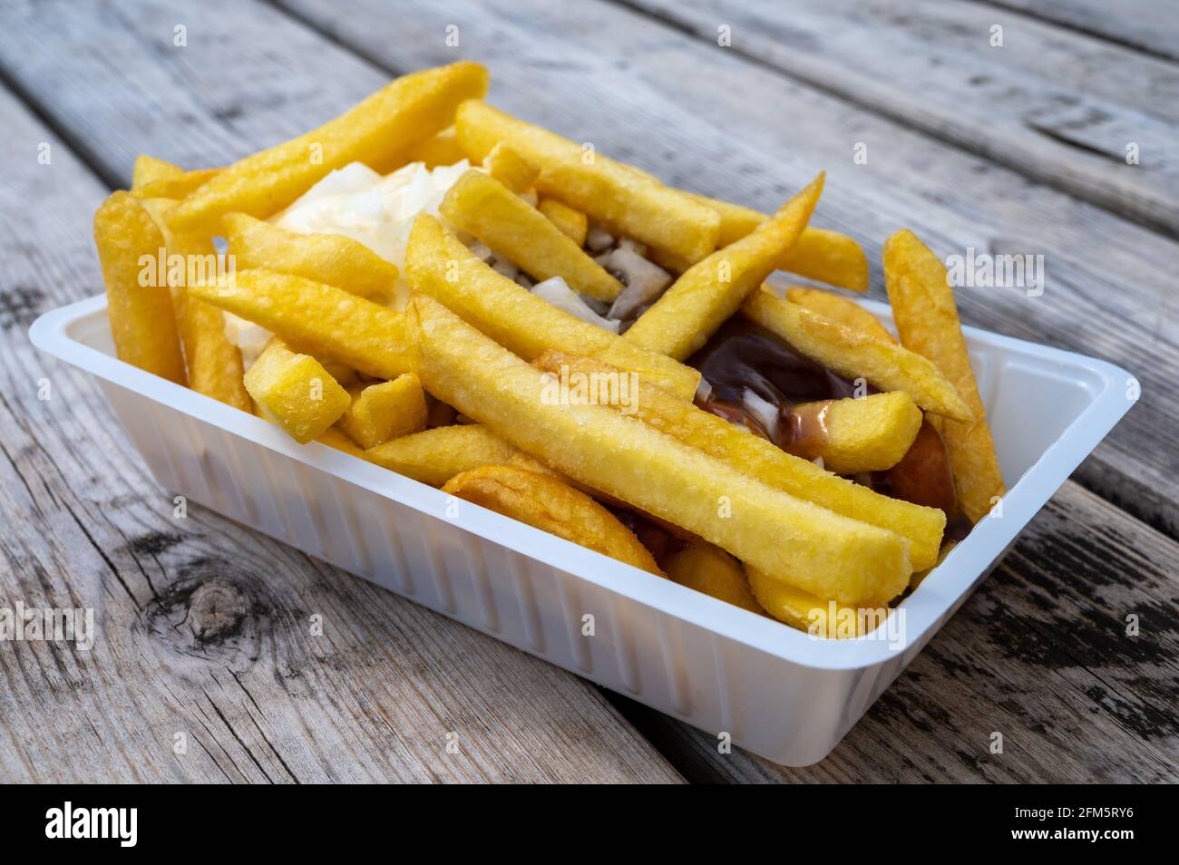 Portion Of French Fried Potato Chips With Curry And Mayonnaise Sauce portion-of-french-fried-potato-chips-with-curry-and-mayonnaise-sauce