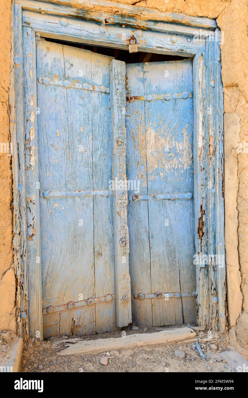 Al Hamra.  Ad Dakhiliyah Region, Oman. Wooden door in old section of the town with abandoned ruined houses . Stock Photo
