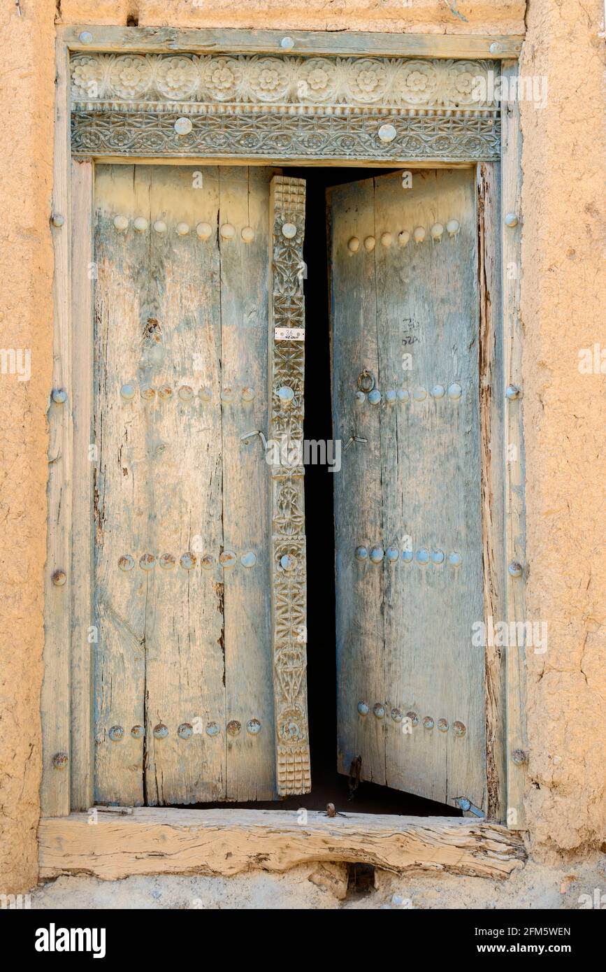 Al Hamra.  Ad Dakhiliyah Region, Oman. Wooden door in old section of the town with abandoned ruined houses . Stock Photo