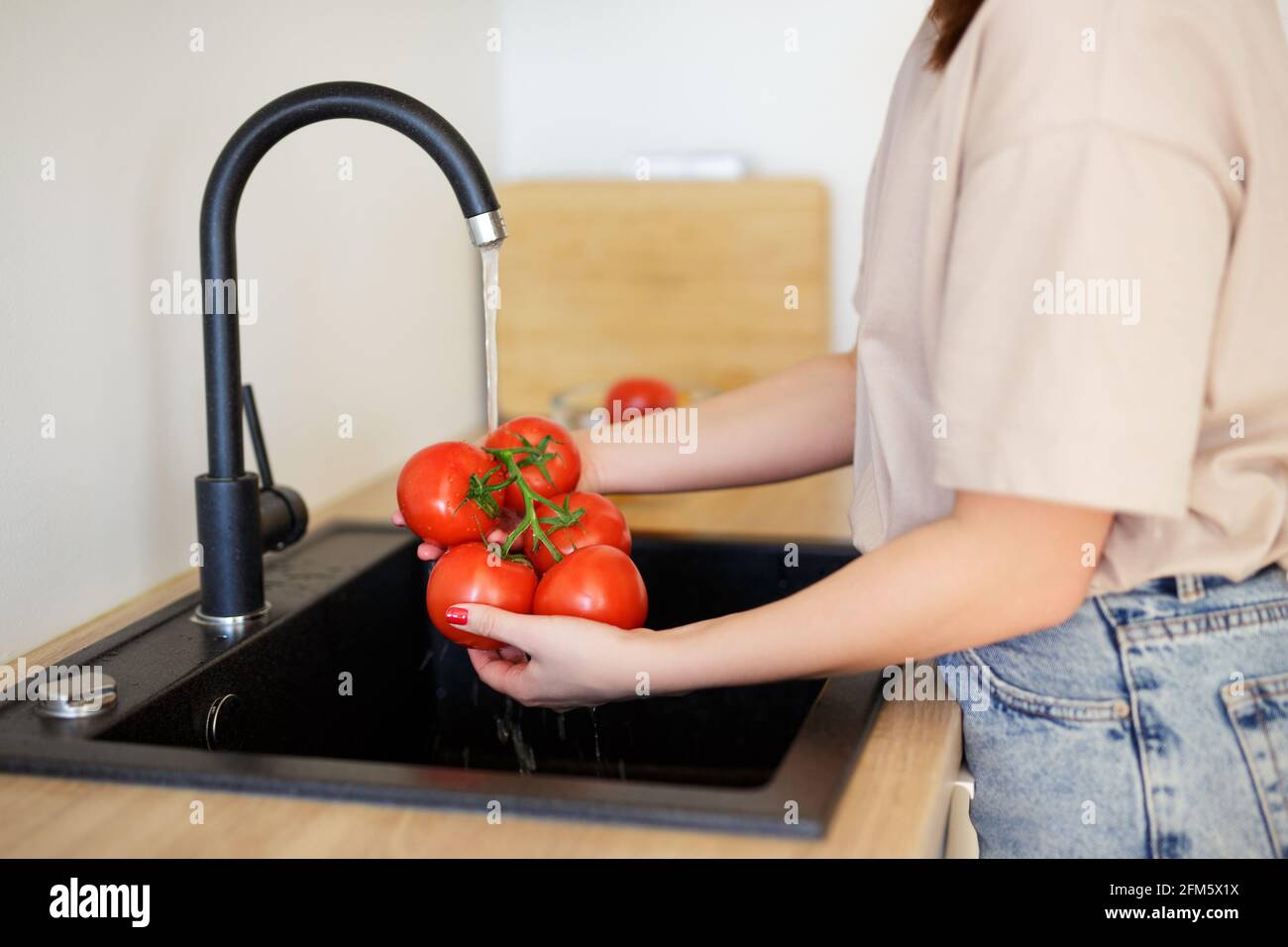 woman washing tomatoes under water before cooking Stock Photo