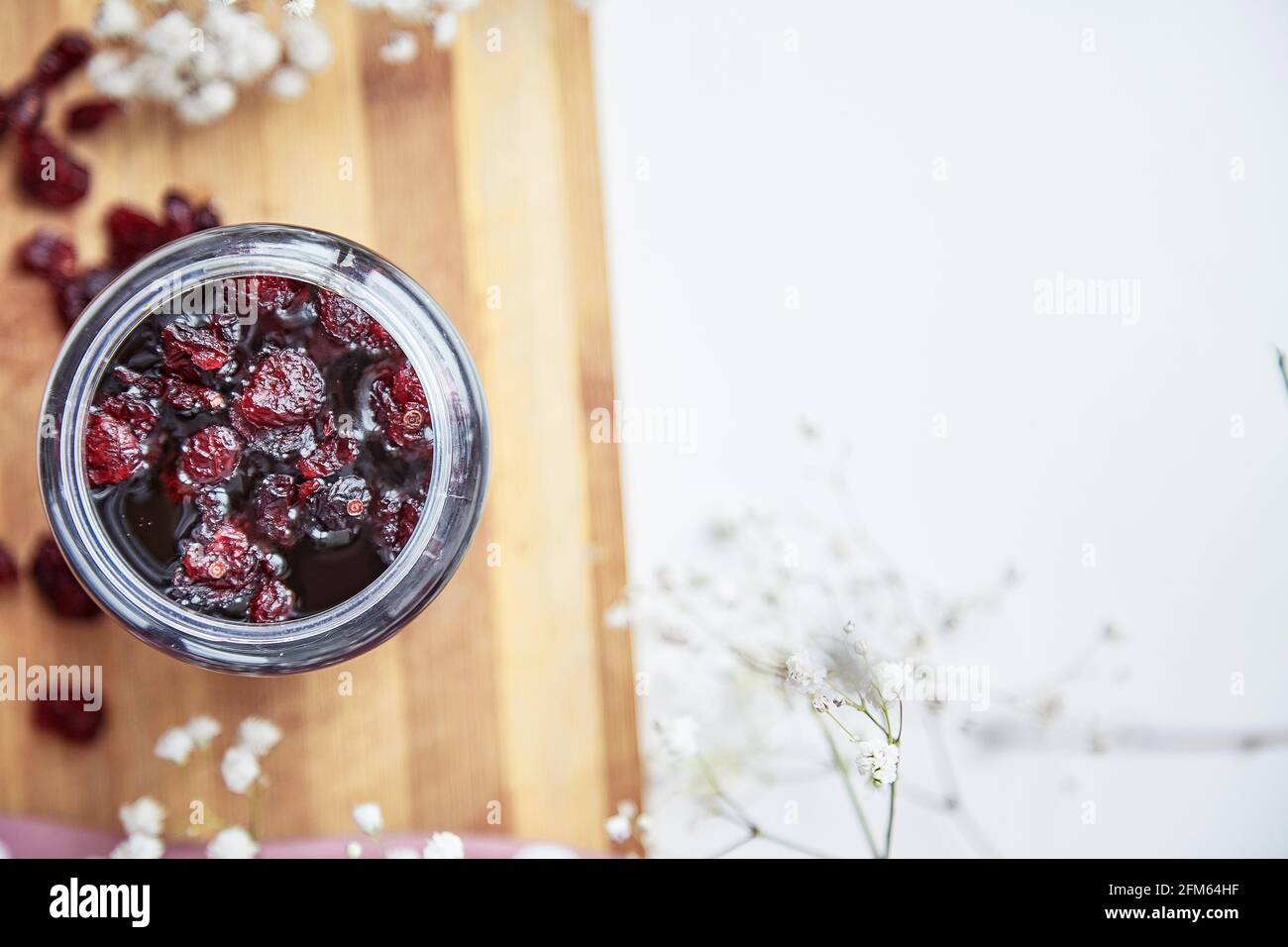Healthy fermented honey product with cranberry, probiotics. Food preservative. Delicious recipe concept. Anti-viral food. Top view. Decoration with gypsophila flower. Copy space Stock Photo
