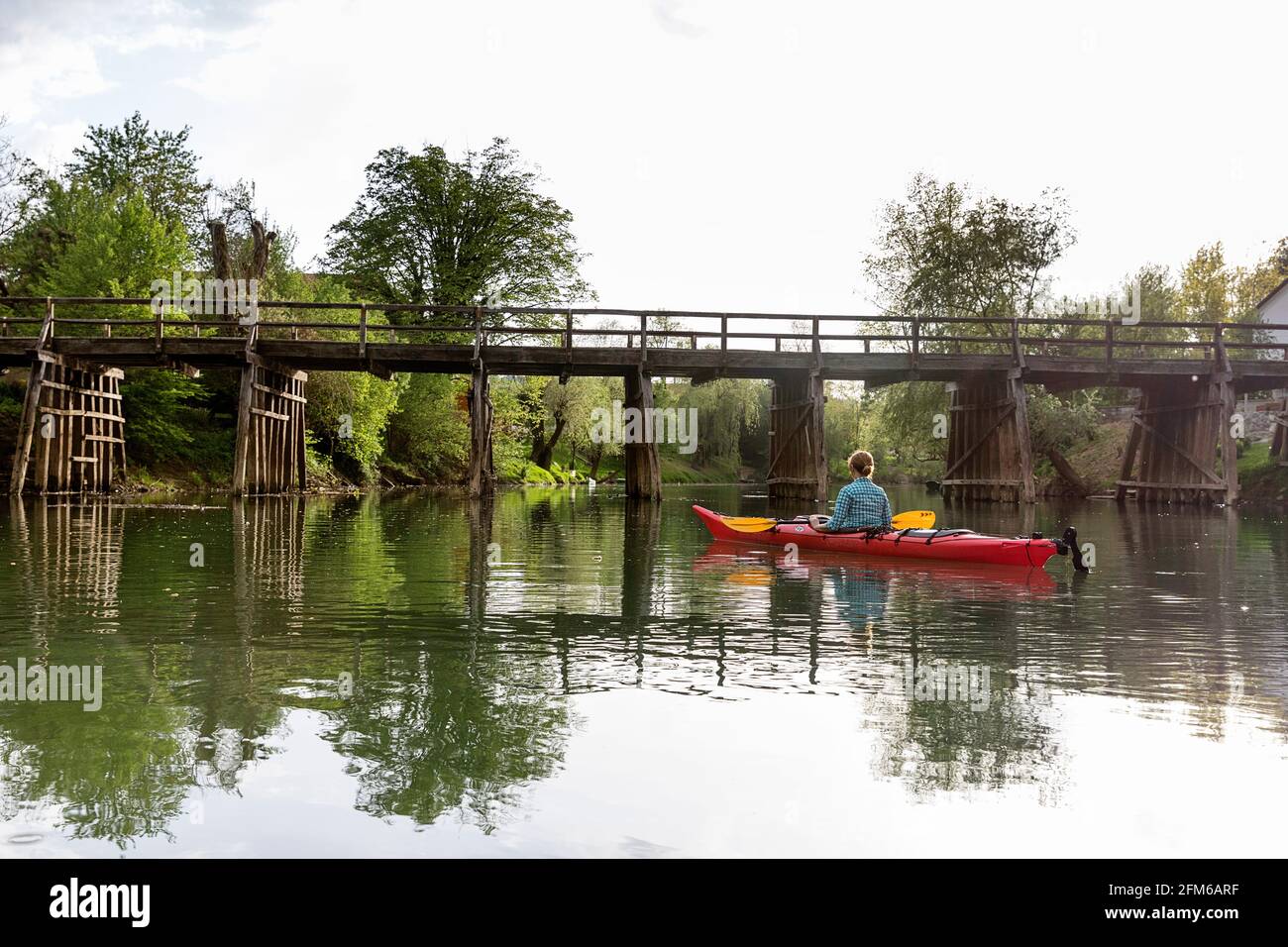 Woman kayaking to wooden bridge over the river Krka in Slovenia, with the  sourounding small town Kostanjevica Stock Photo - Alamy