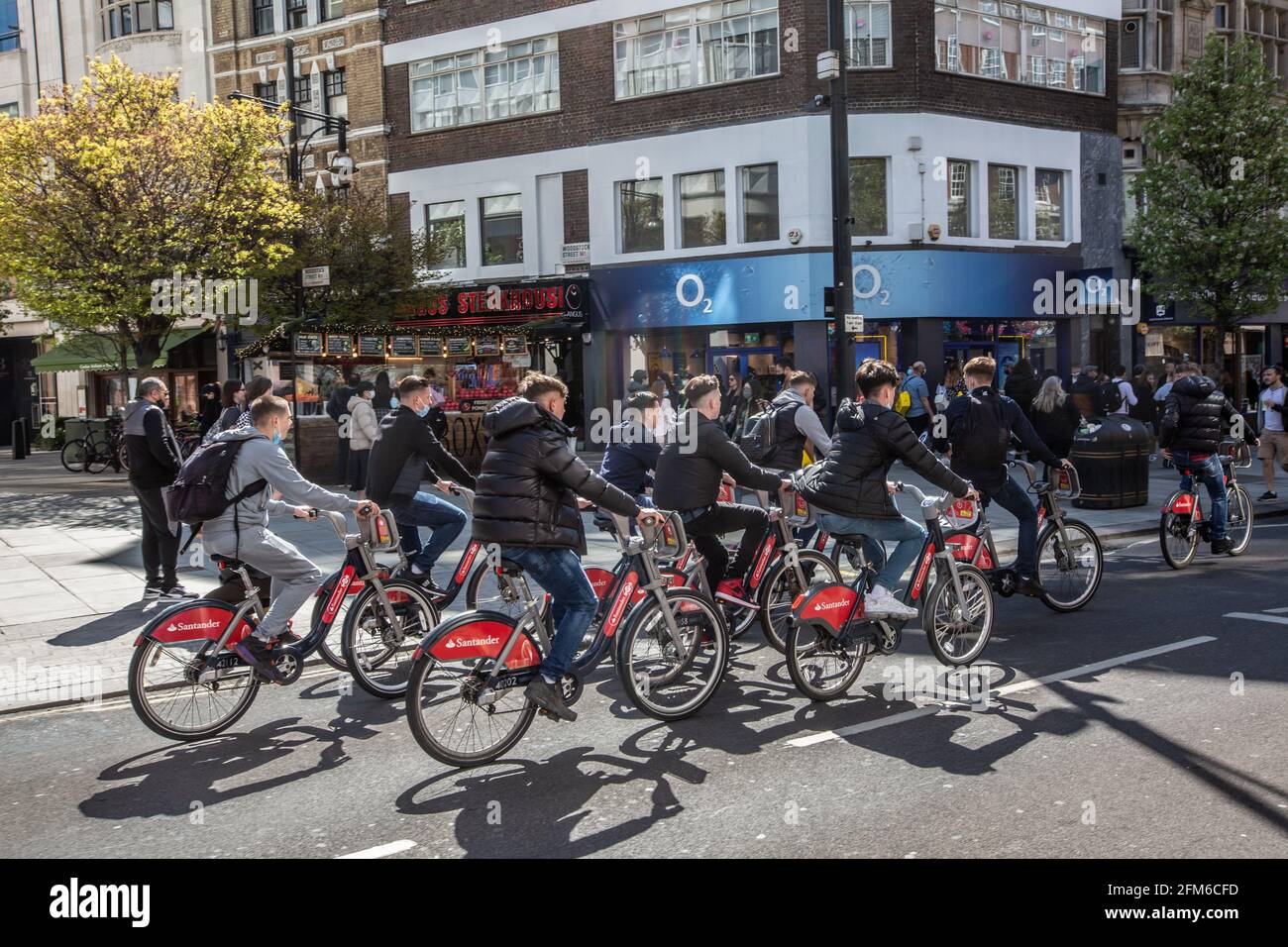Group of teenage boys cycling along Oxford Street causing traffic to halt on the busy high street in Central London, England, UK Stock Photo