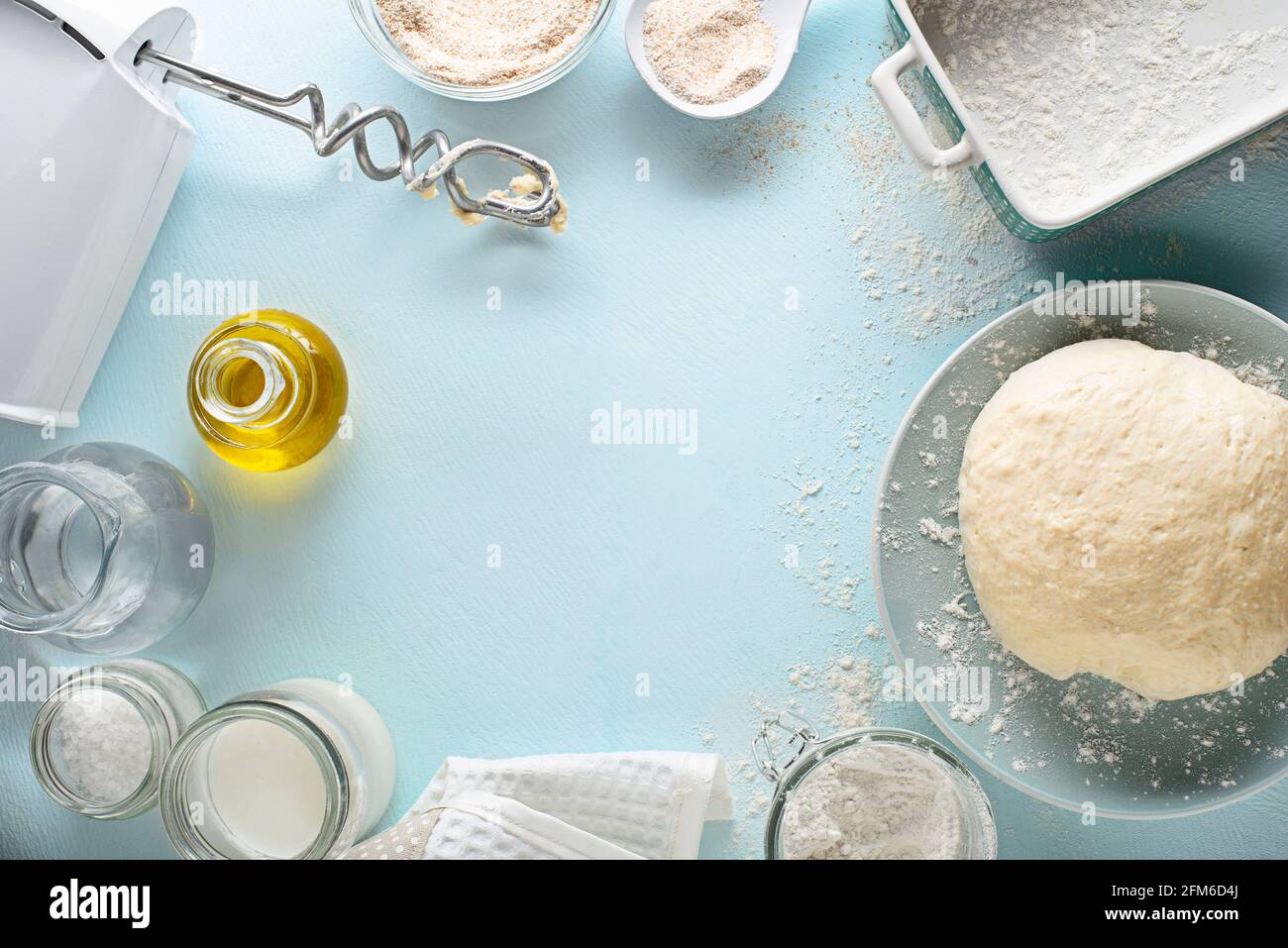 Ingredients for making and baking homemade bread on blue table background. Mixing and kneading the dough Stock Photo