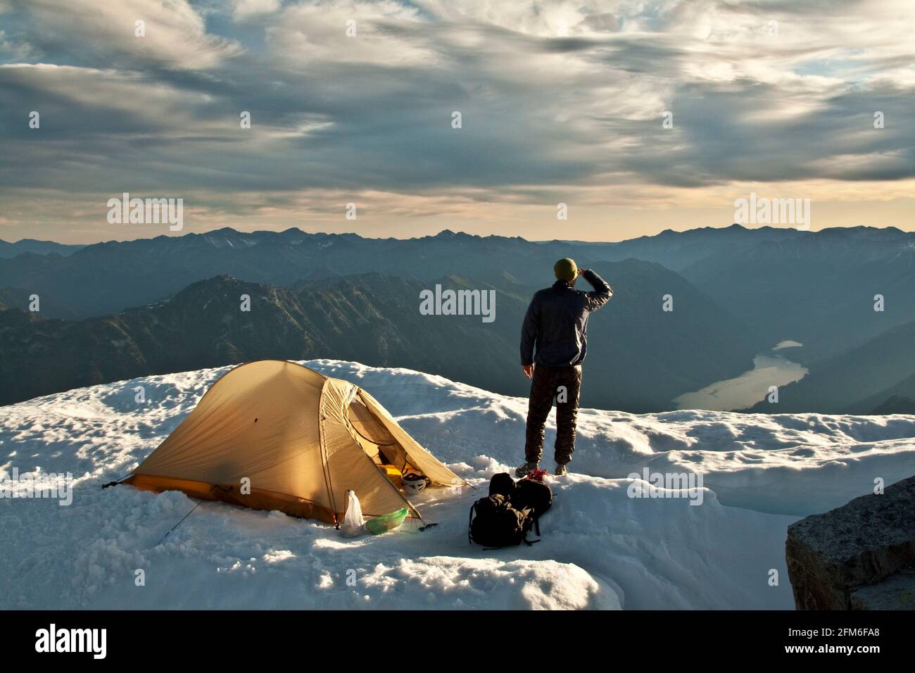 Hiker stands next to tent on mountain summit, Whistler, B.C. Canada. Stock Photo