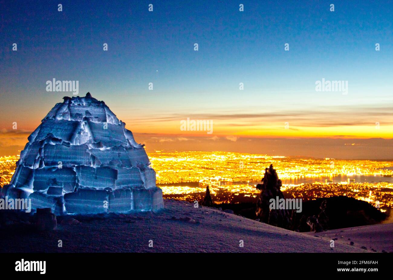 Igloo on mountain summit above city lights of Vancouver, Canada. Stock Photo