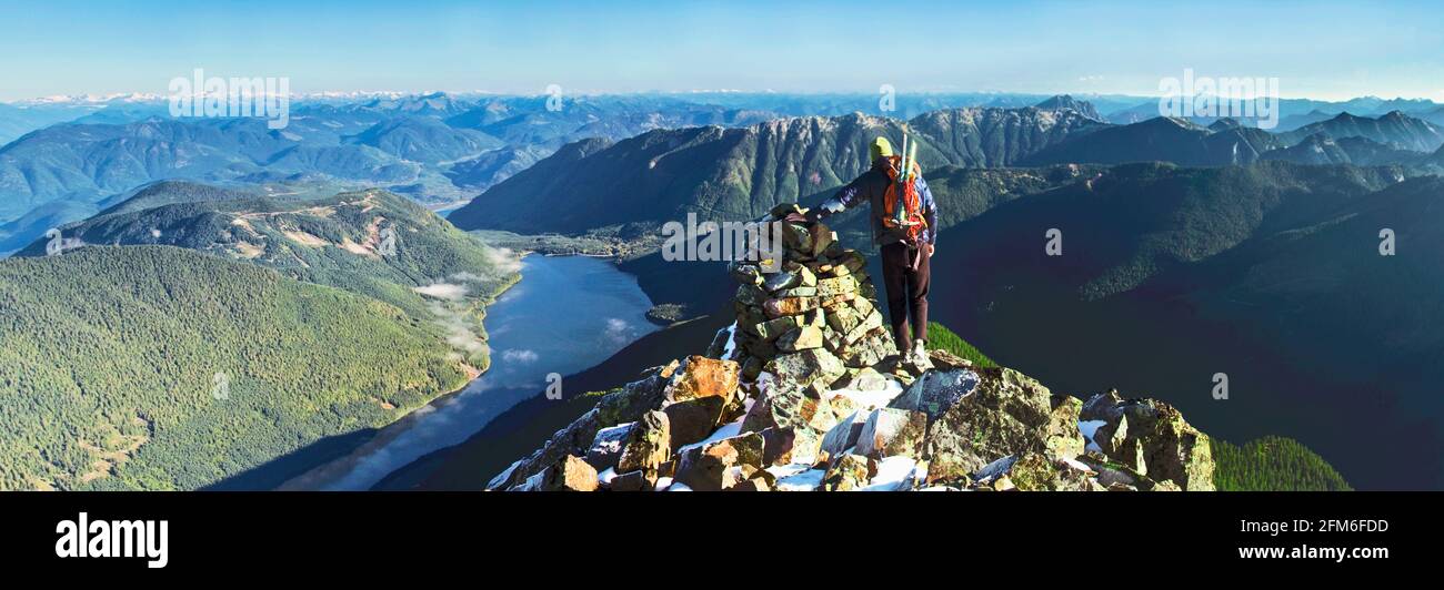 Rear view of backpacker standing on rocky mountain summit, scenic view Stock Photo