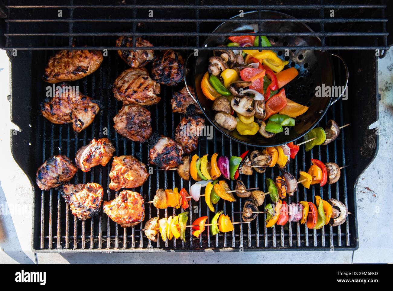Overhead of vegetable skewers and chicken on the grill of a gas bbq