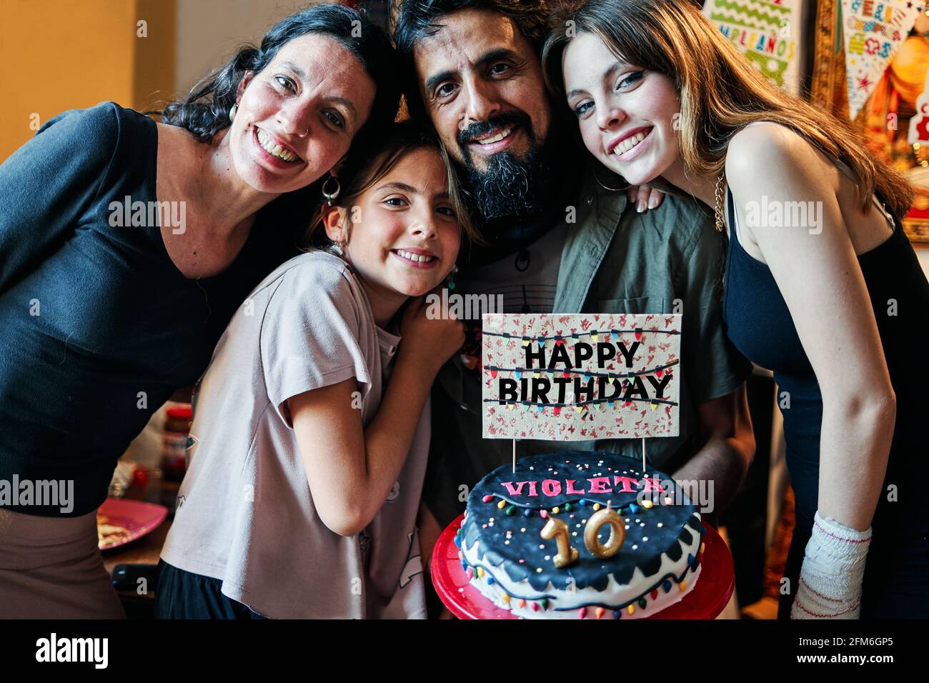 Portrait of a Latino family celebrating little girl's 10th birthday Stock Photo
