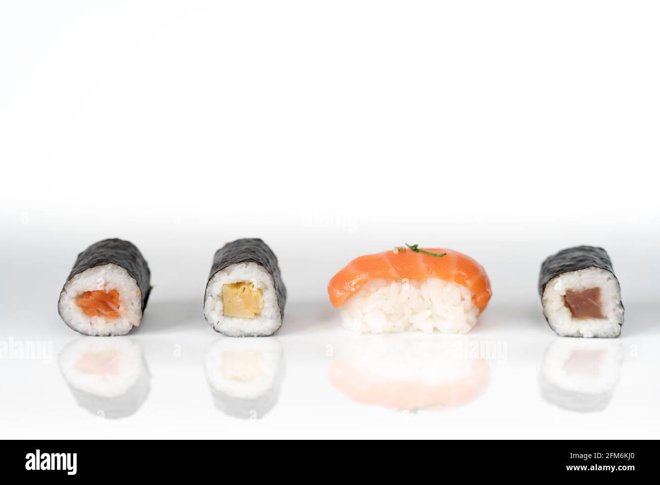 Three maki rolls and a salmon nigiri in a row isolated on white