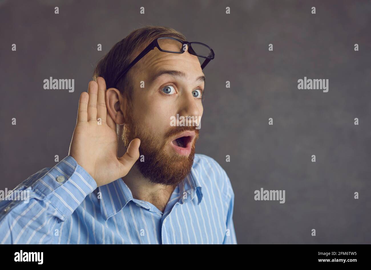 Curious man listening with hand at ear eavesdropping on a shocking gossip at work Stock Photo