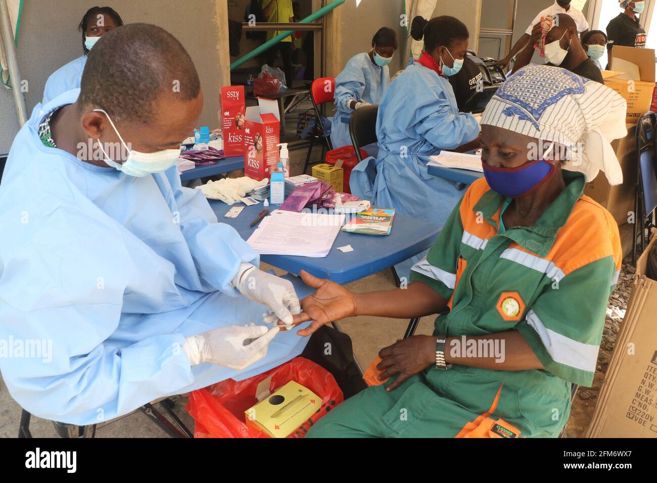 A health worker takes the blood sample of a Lagos state waste bin worker for an HIV/AIDS test on International Workers Day. International Workers Day is celebrated on every May 1, across the World, and it is observed to spread awareness among people, regarding the rights of workers and to mark their achievements. Lagos, Nigeria. Stock Photo