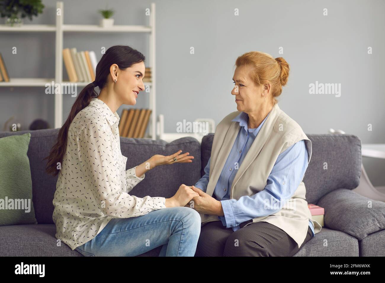 Happy daughter and understanding supportive senior mother sitting on sofa and talking Stock Photo