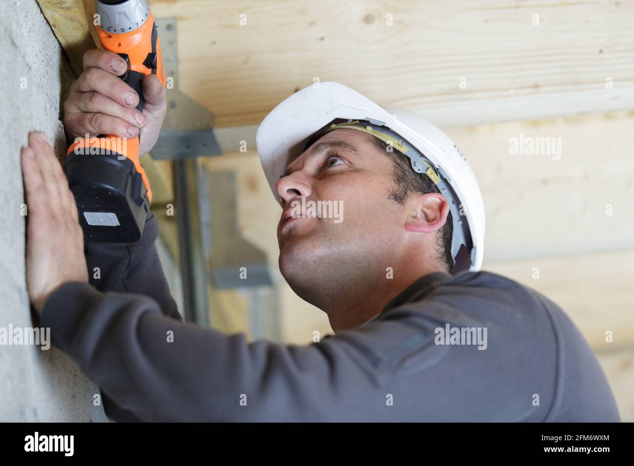 male worker is drilling a hole on the ceiling Stock Photo