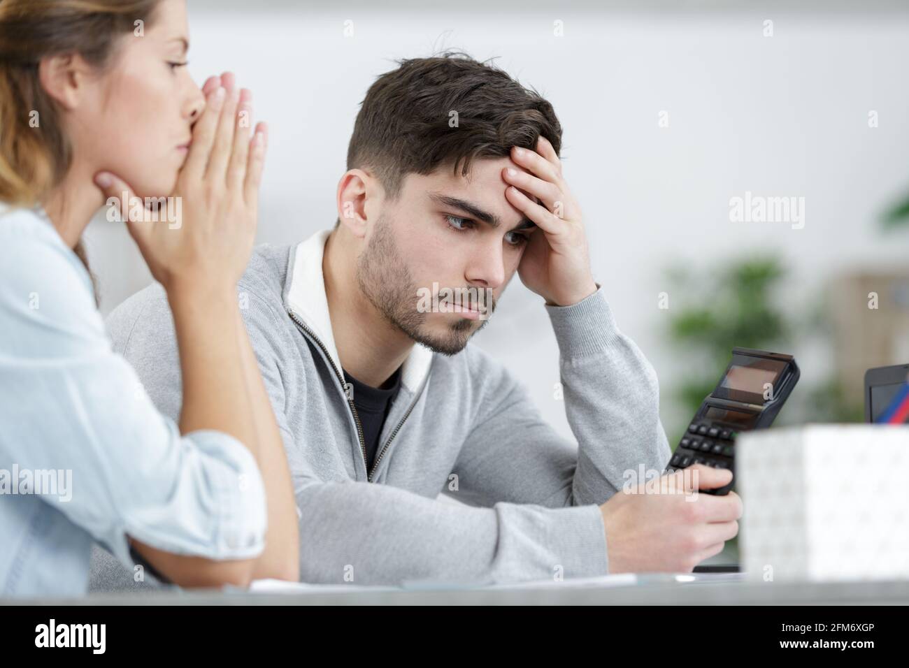 focused couple sits on couch using calculator Stock Photo Alamy