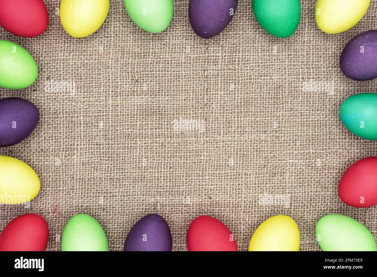 Multicolored Easter eggs on a burlap background. Easter frame. Stock Photo