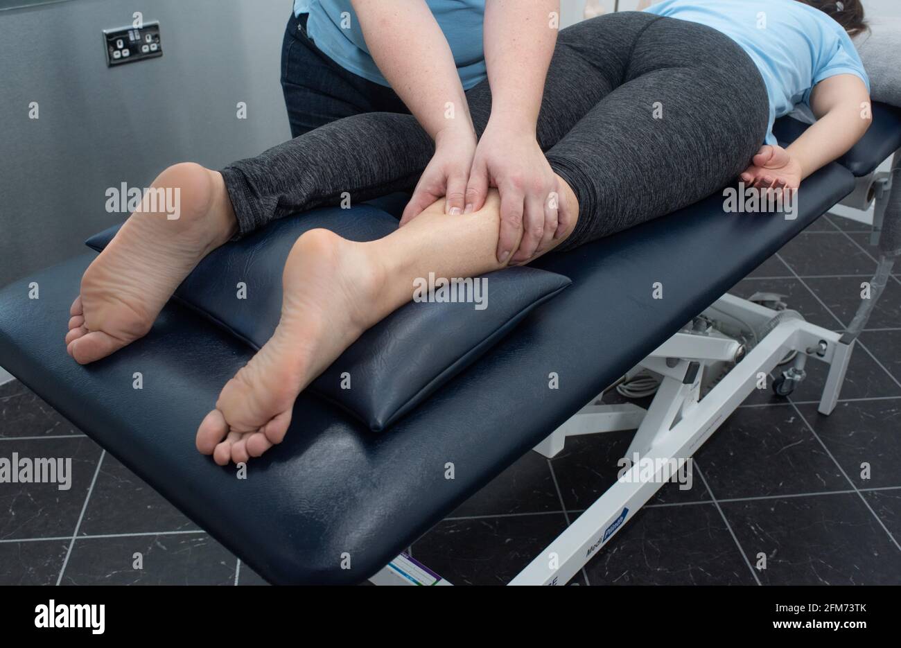 A massage therapist or physio massages a womans legs Stock Photo