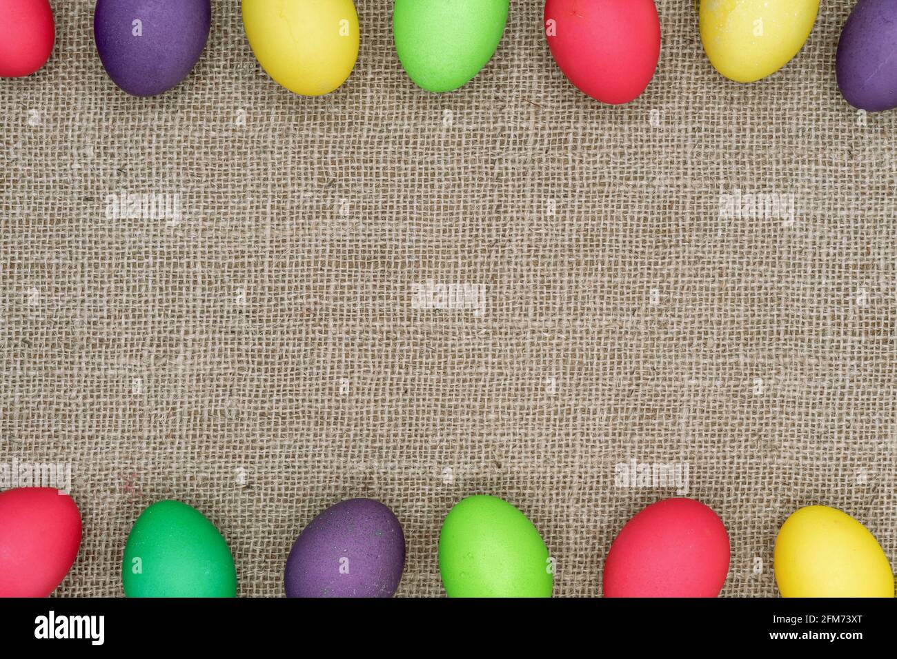 Multicolored Easter eggs on a burlap background. Easter frame. Stock Photo