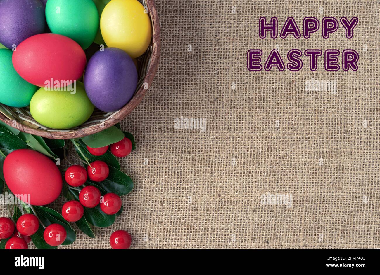 Easter eggs in a wicker basket, red berries and the inscription "Happy Easter". Stock Photo