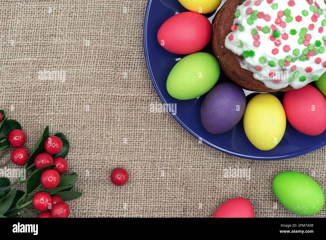 Plate with colorful Easter eggs, Easter cake and red berries. Stock Photo