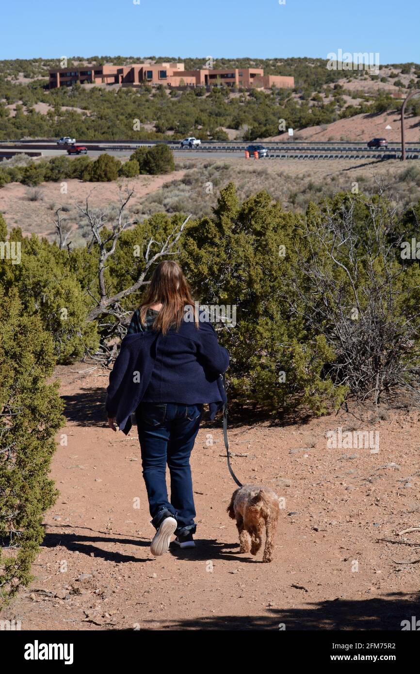 A woman walks her dog along a nature trail in Santa Fe, New Mexico. Stock Photo