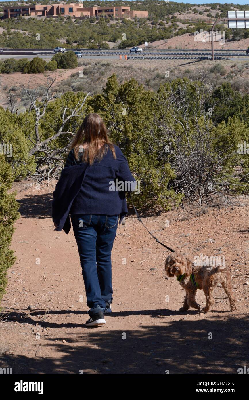 A woman walks her dog along a nature trail in Santa Fe, New Mexico. Stock Photo