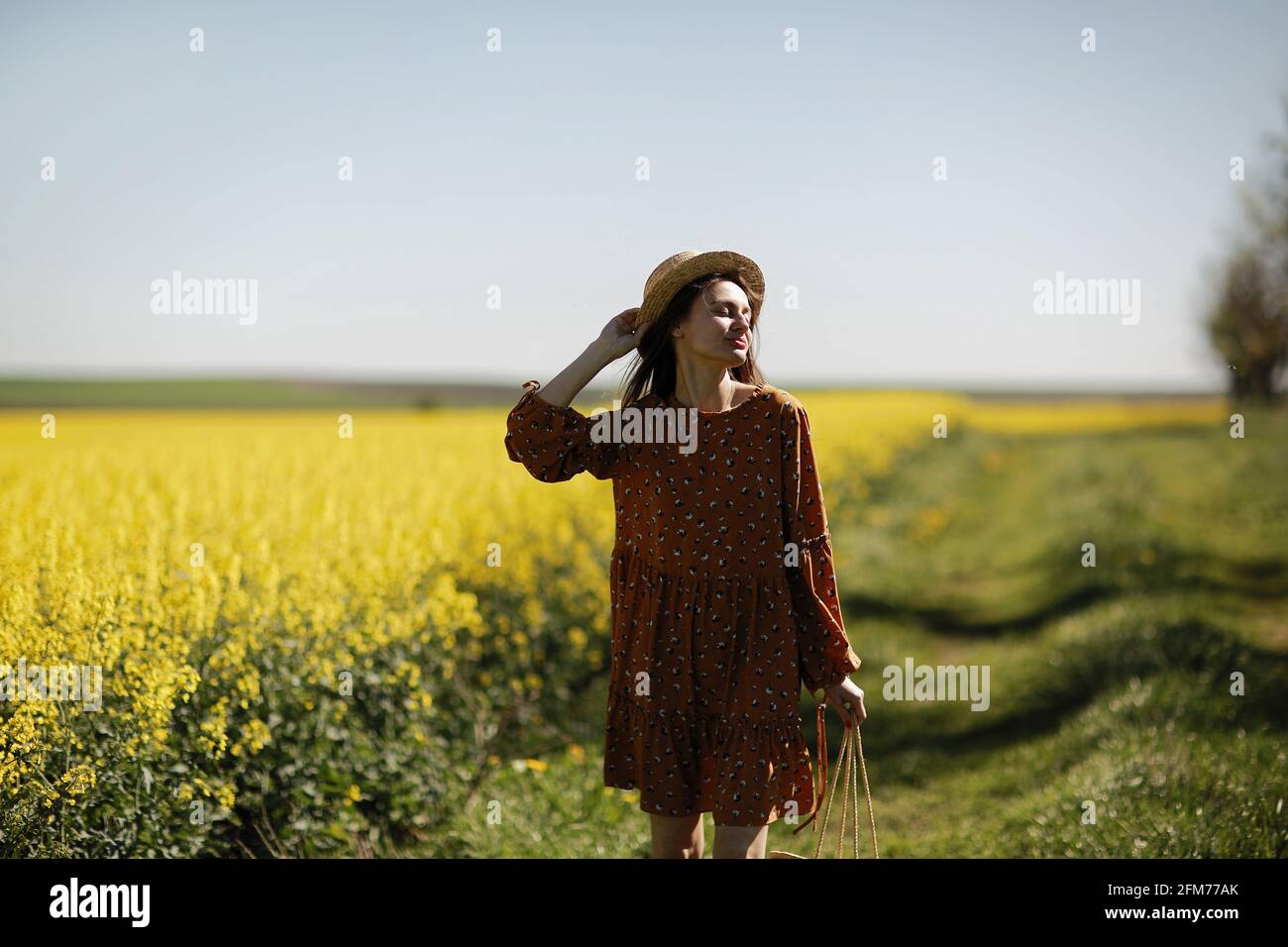 beautiful young woman walks in a field of yellow rapeseed. Girl ...