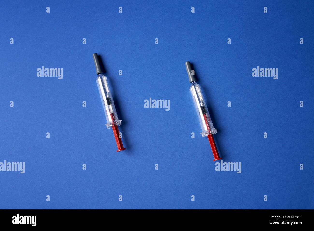 two small injectors on dark blue background Stock Photo - Alamy