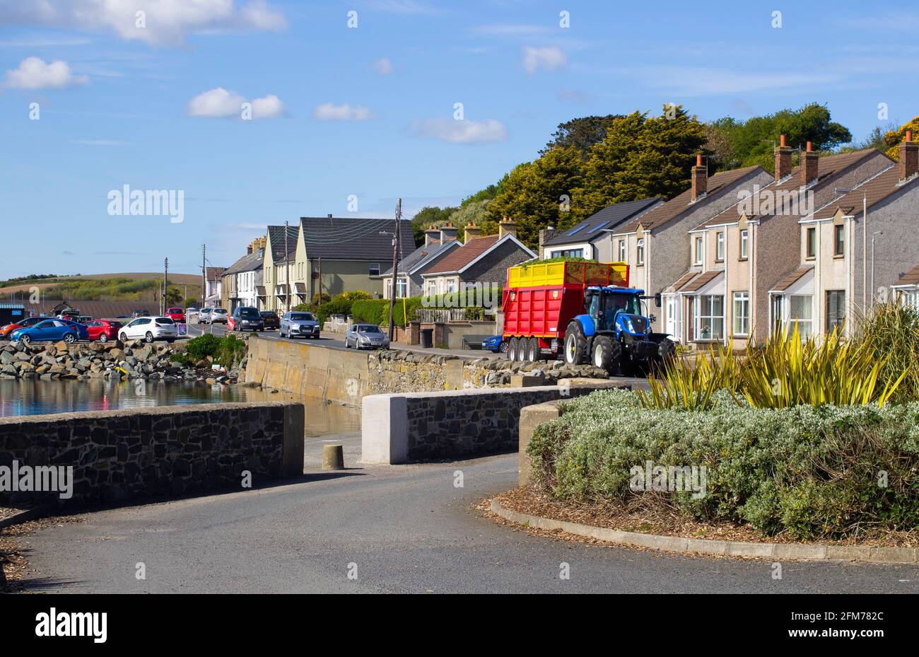 29 April 2021 A large tractor and trailer with a load of silage on the main street of the village of Kircubbin on Strangford Lough in County Down Nort Stock Photo