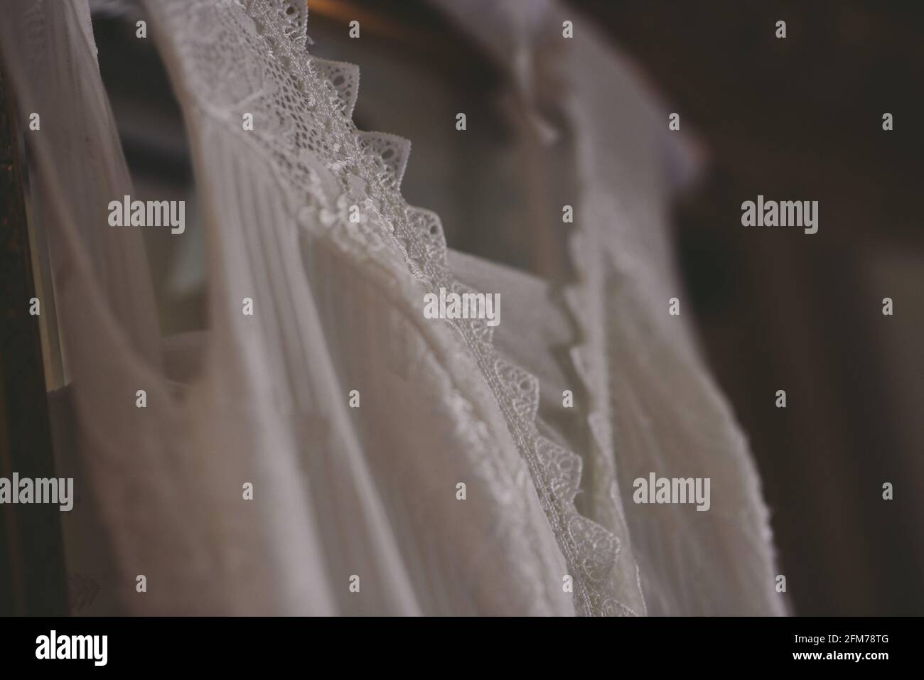 close up of a sleeveless lace wedding dress hanging Stock Photo