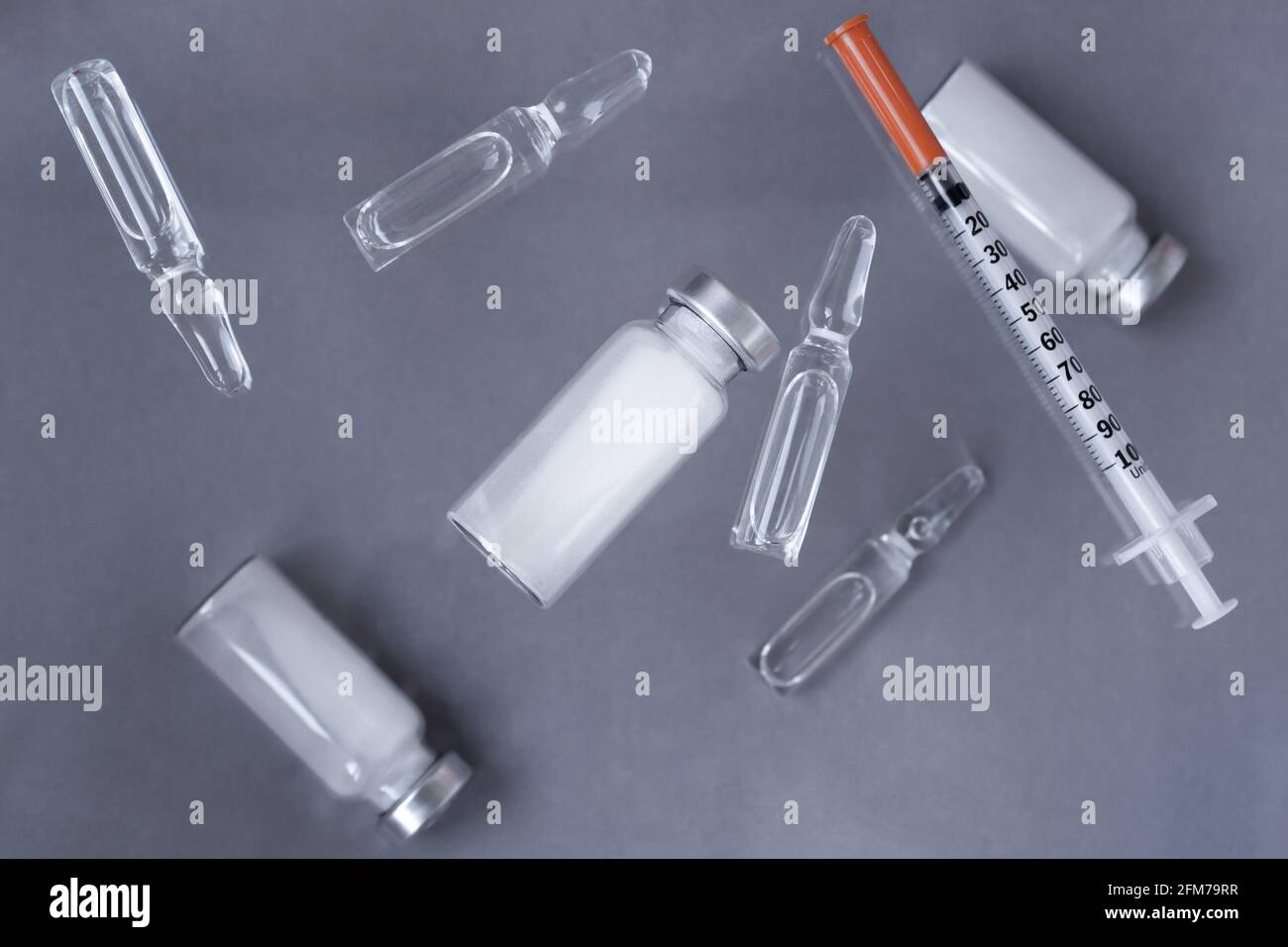 Medicines in vials and ampoules, undiluted and liquid for injections, syringes for injections on a gray background. Stock Photo