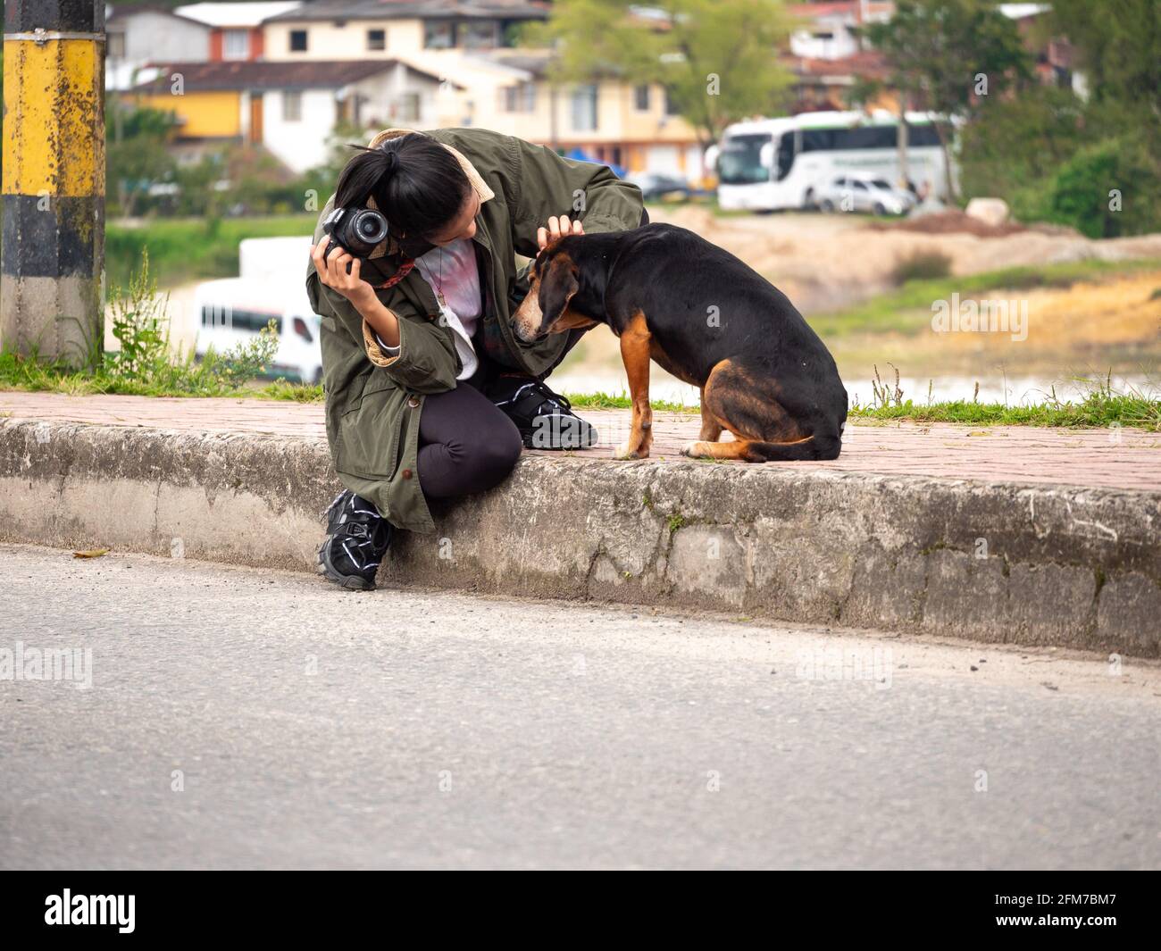 Guatape, Antioquia / Colombia - April 4 2021: Young Short Hispanic Woman in Blue Jeans and Black Shirt Takes Picture with Compact Mirrorless Camera Stock Photo