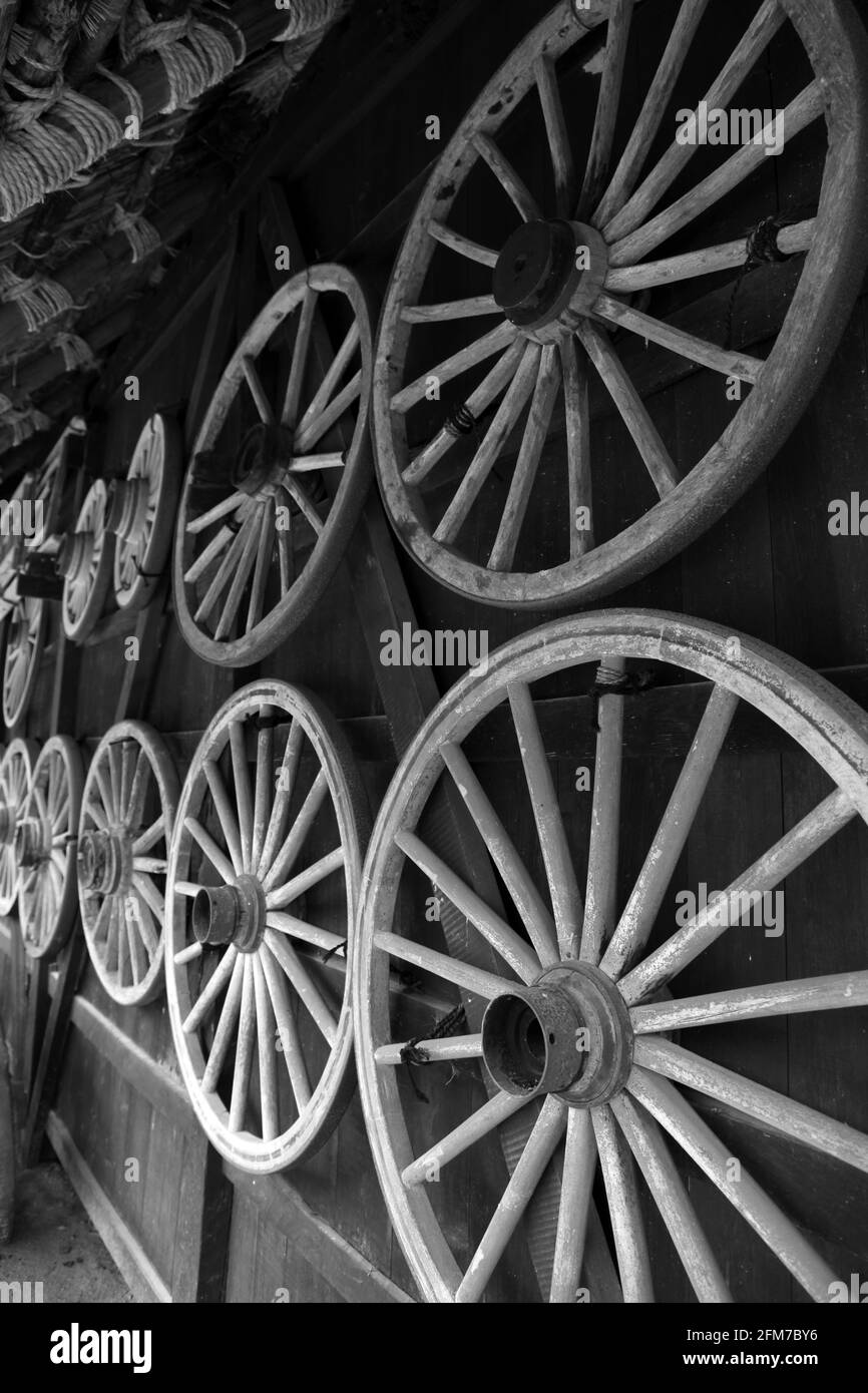 Traditional wooden spoked wagon wheels hanging on a wall in Takayama Japan. Black and White Stock Photo