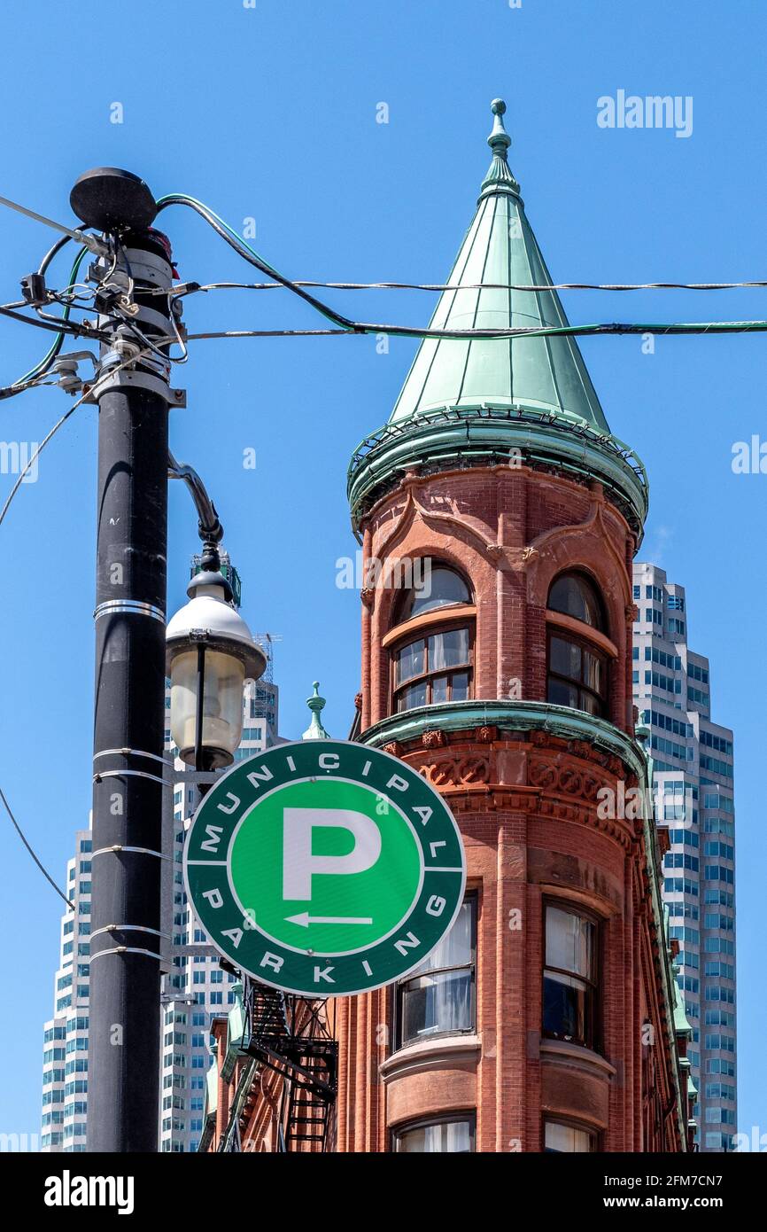 The Flatiron or Gooderham Building framed on a green P parking sign in Toronto, Canada Stock Photo