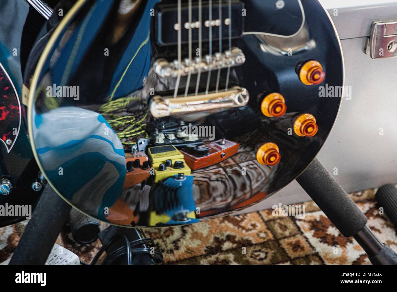 Effects pedals reflected on black Les Paul. Stock Photo