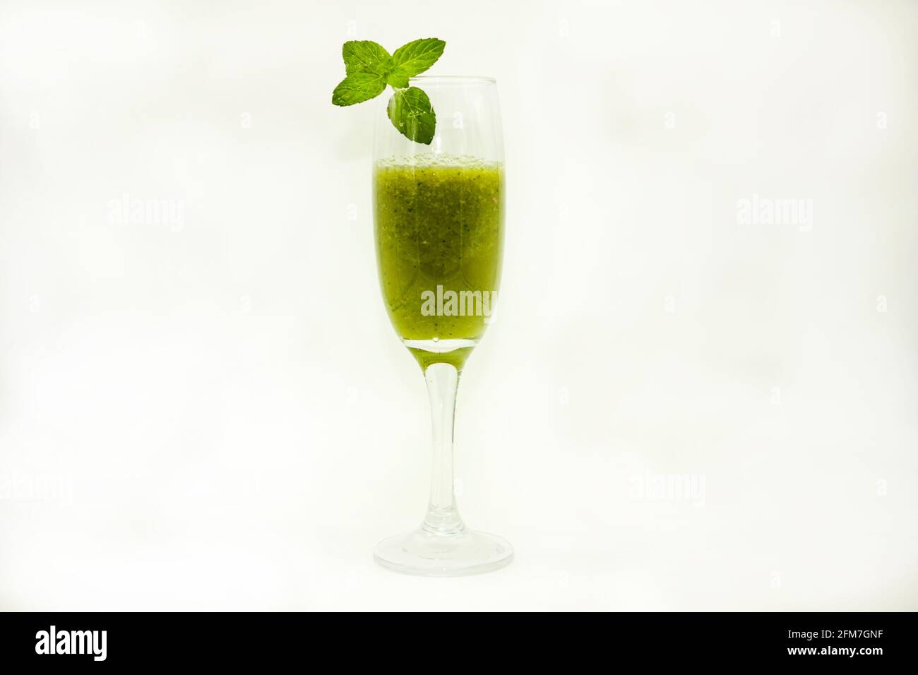 Green juice herbal vegan drink served in piping glass goblet with good