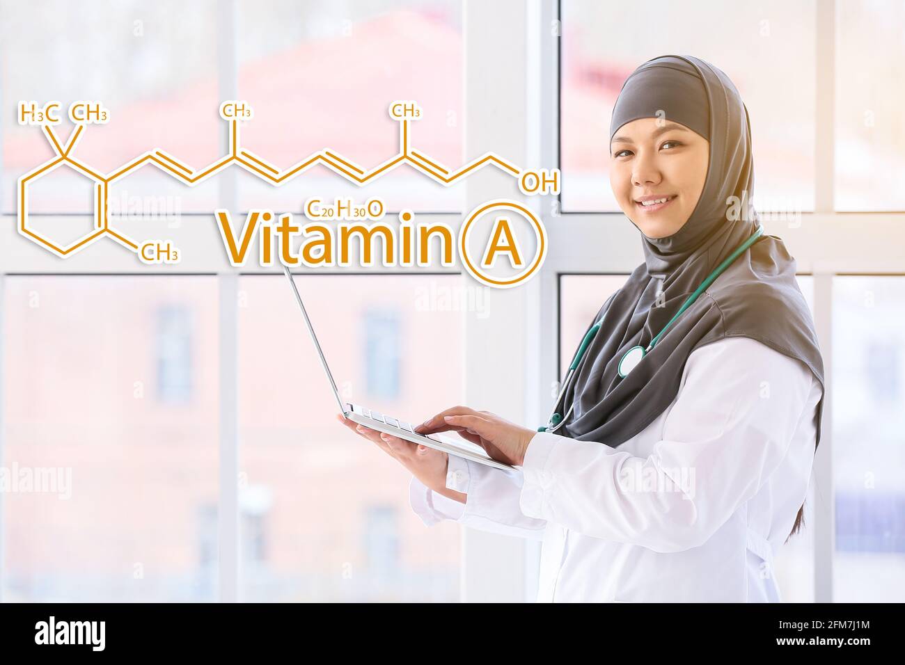 Muslim doctor with laptop and chemical structural formula of vitamin A in clinic Stock Photo