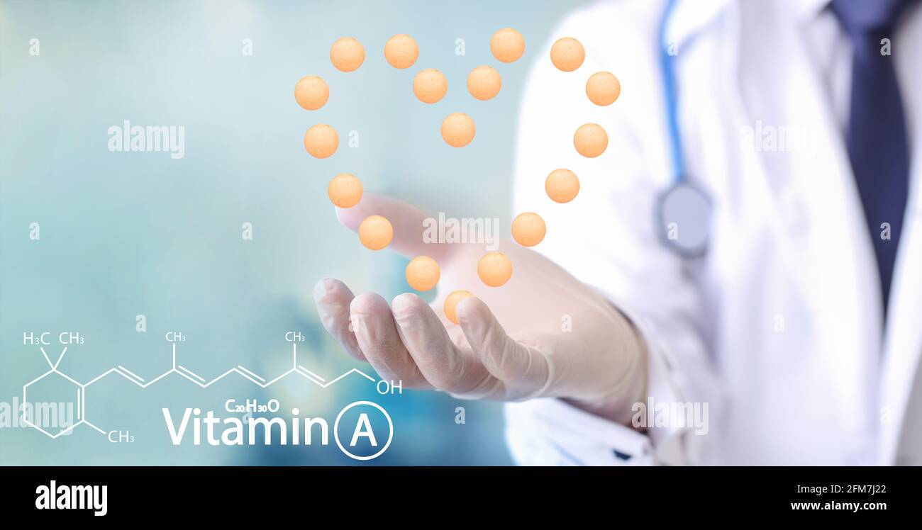 Doctor with vitamin A pills in shape of heart in clinic, closeup Stock Photo