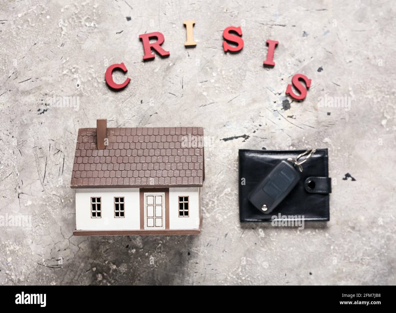 Model of house with wallet, car key and word CRISIS on grunge ...