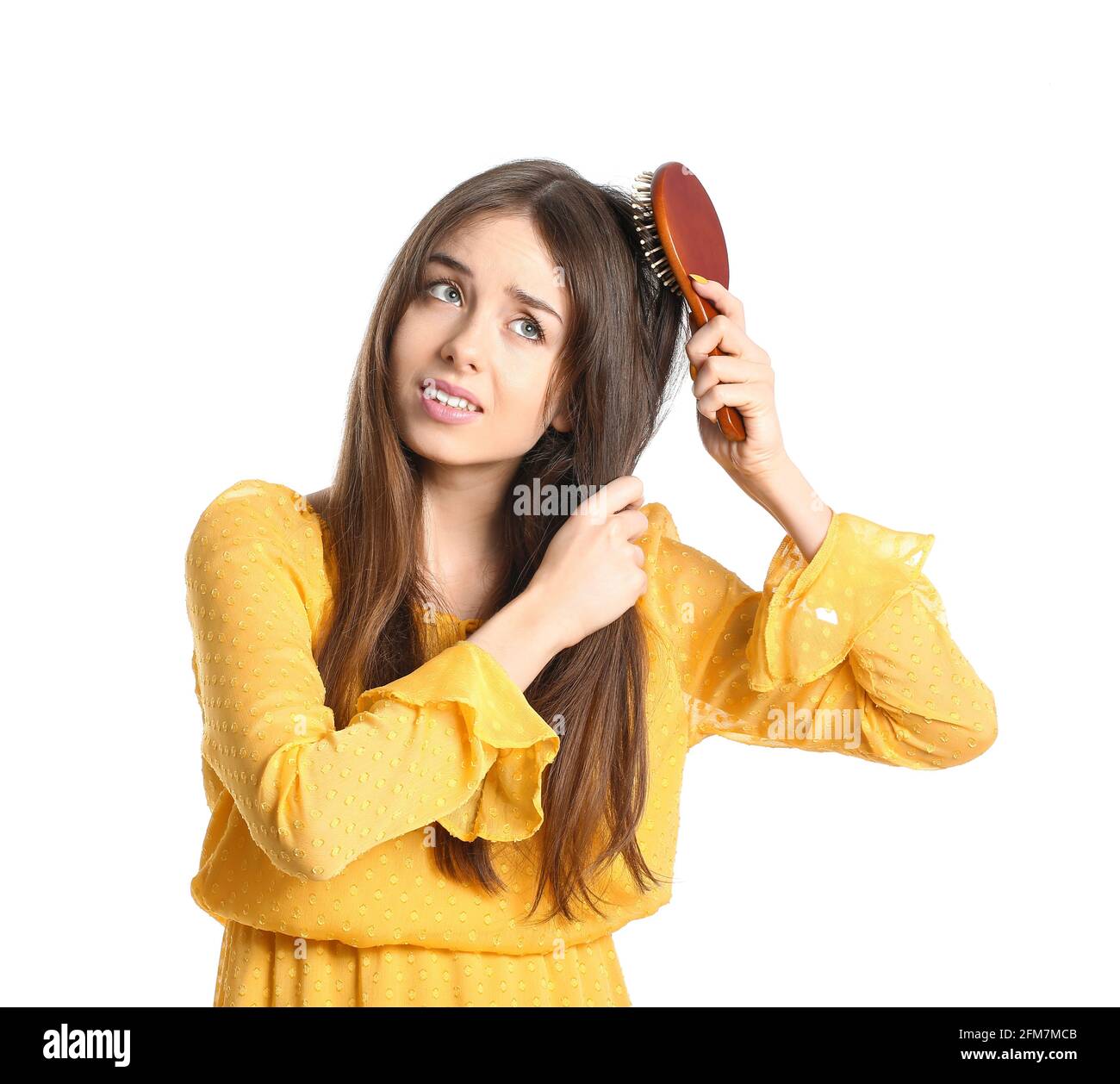 Sad young woman with hair brush on white background Stock Photo - Alamy