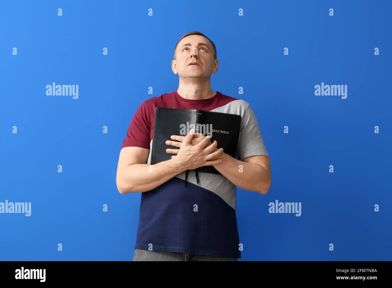 Man with Bible on color background Stock Photo