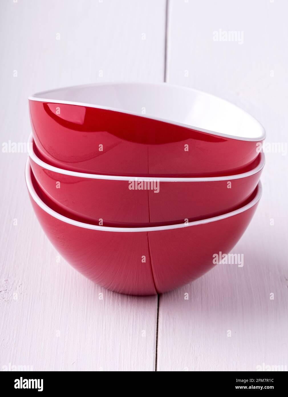 empty red Salad Bowl and three cups on a white wooden table Stock Photo