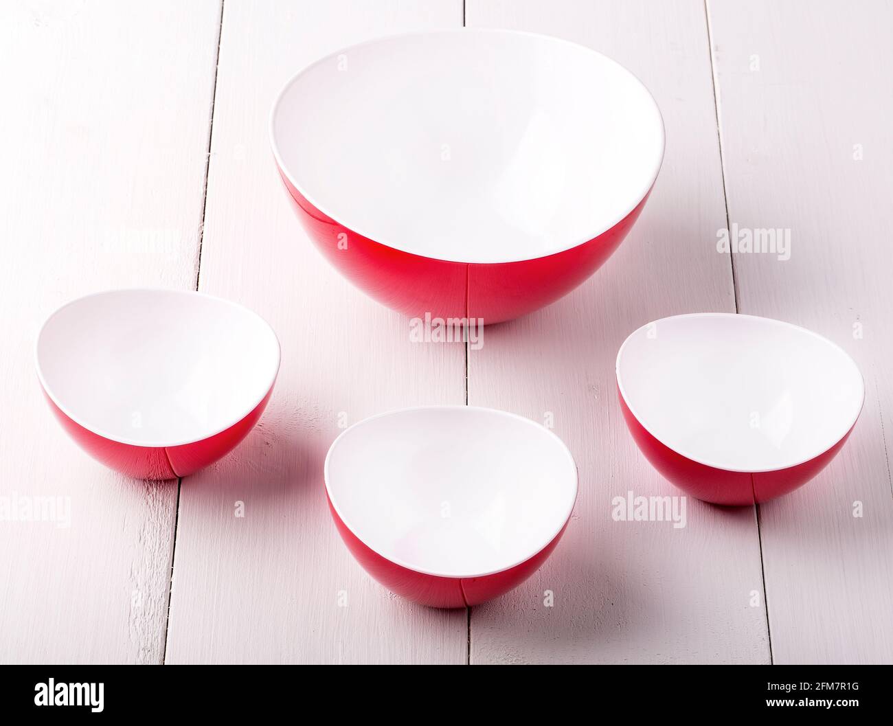 https://c8.alamy.com/comp/2FM7R1G/an-empty-red-salad-bowl-and-three-cups-on-a-white-wooden-table-2FM7R1G.jpg