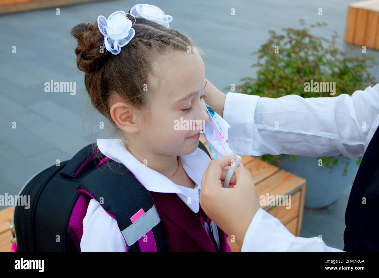 Mother is putting on her daughter protection mask before school. Schoolgirl. New normal. Coronavirus protection Stock Photo