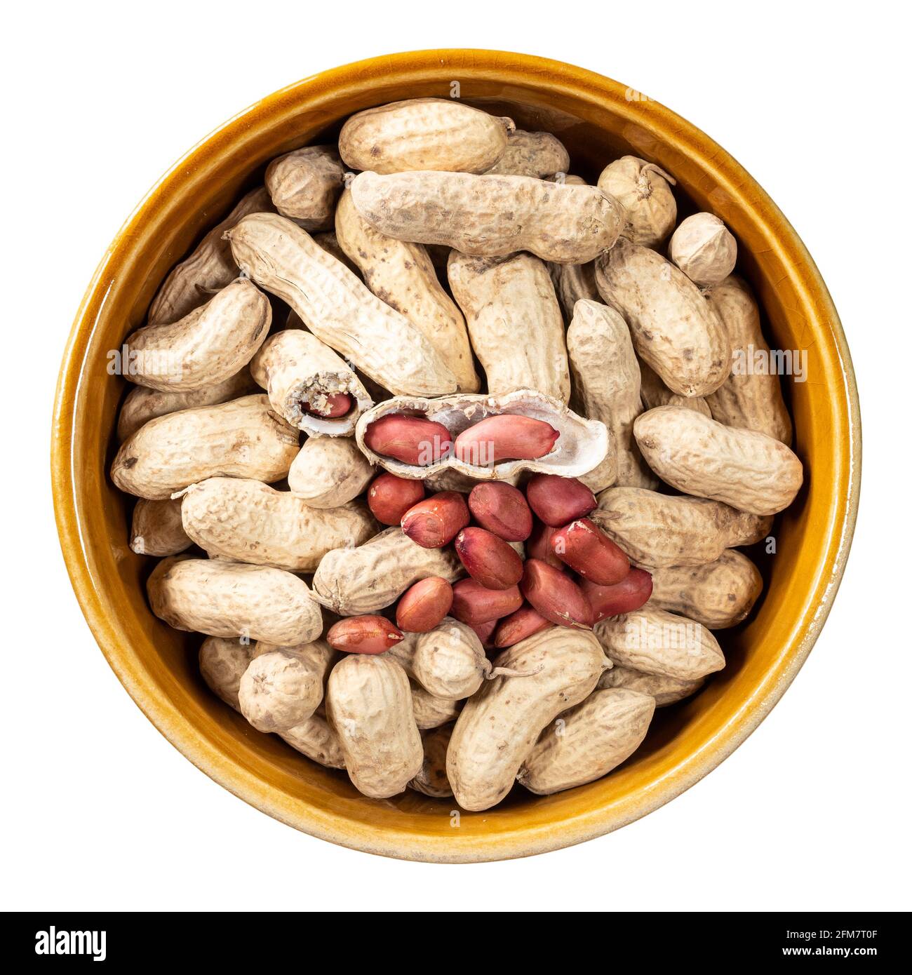 top view of peeled and unpeeled peanuts in round ceramic bowl cutout on white background Stock Photo