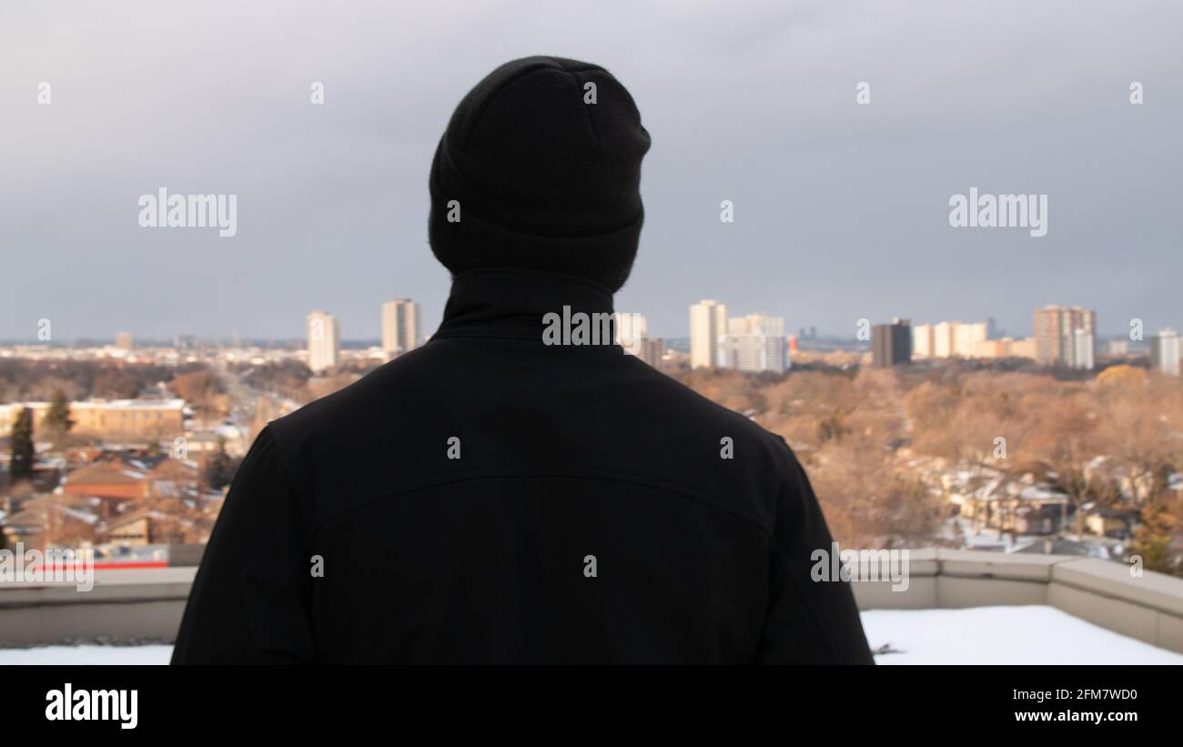 Rear view of male security in uniform watching over street from high floor Stock Photo