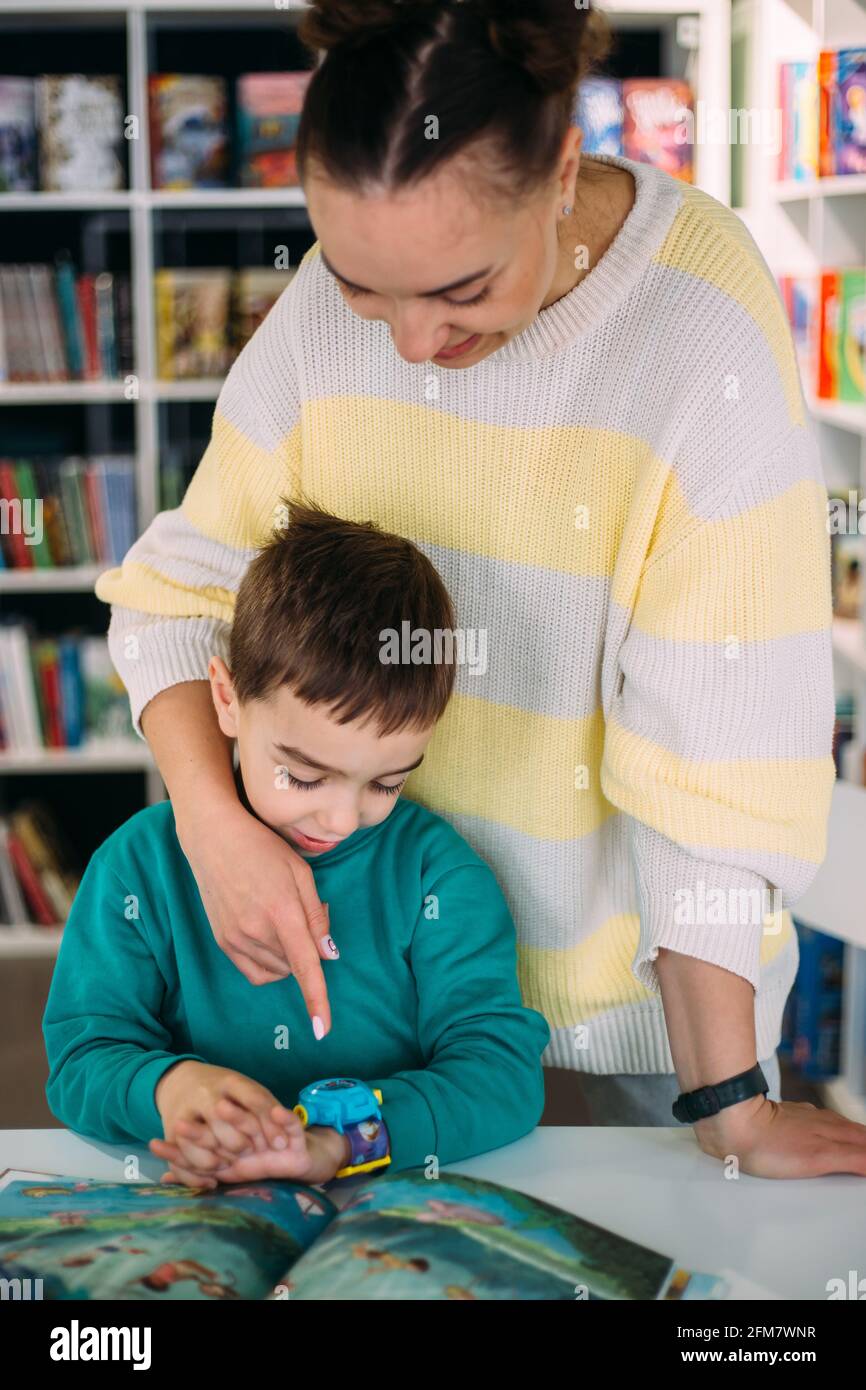 Mom gives her son his first watch. Learning to determine the time by the clock. Stock Photo