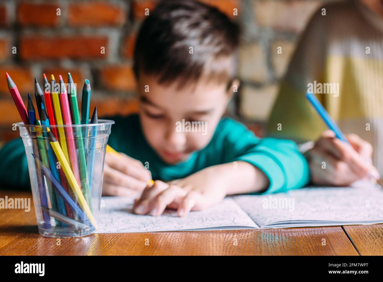 Portrait of a cute happy preschool boy at home or in a cafe draws Stock ...