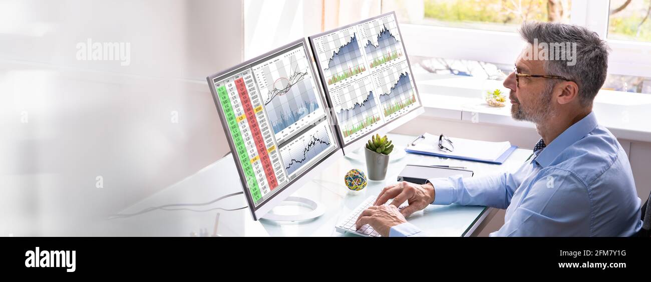 Stock Exchange Analyst Using Multiple Computer Screens Stock Photo