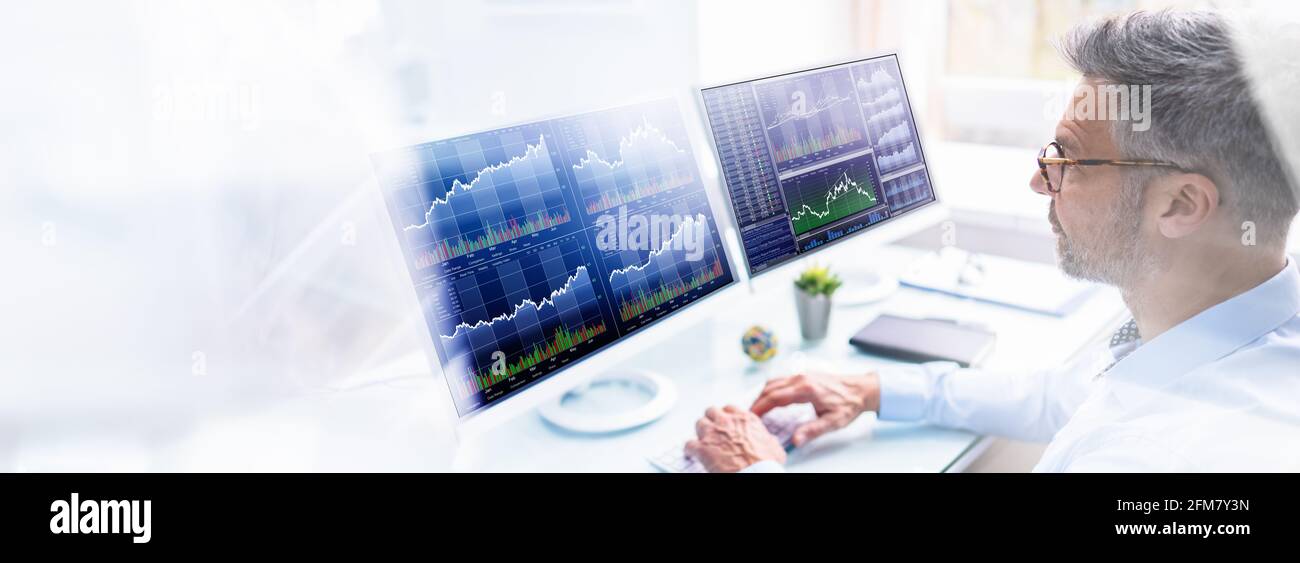 Stock Exchange Analyst Using Multiple Computer Screens Stock Photo